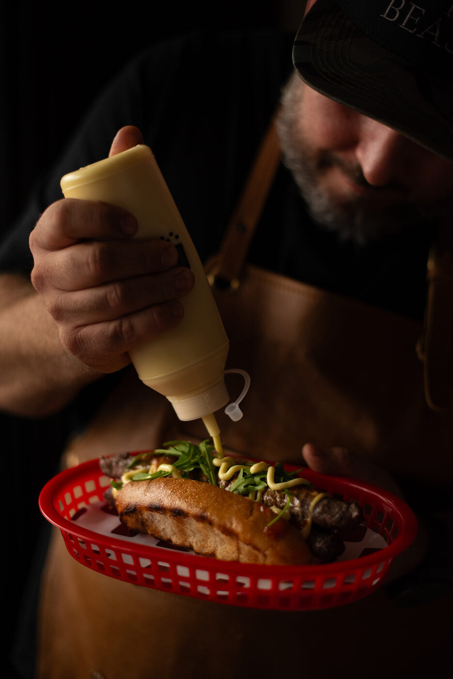 Finishing a BURI boerewors roll with garlic mayo