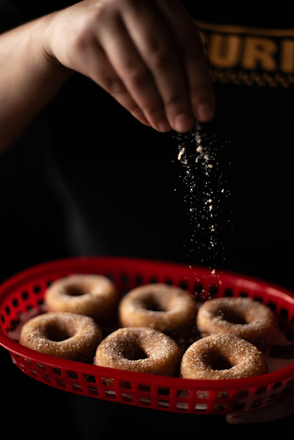 Dusting BURI mini doughnuts with sugar